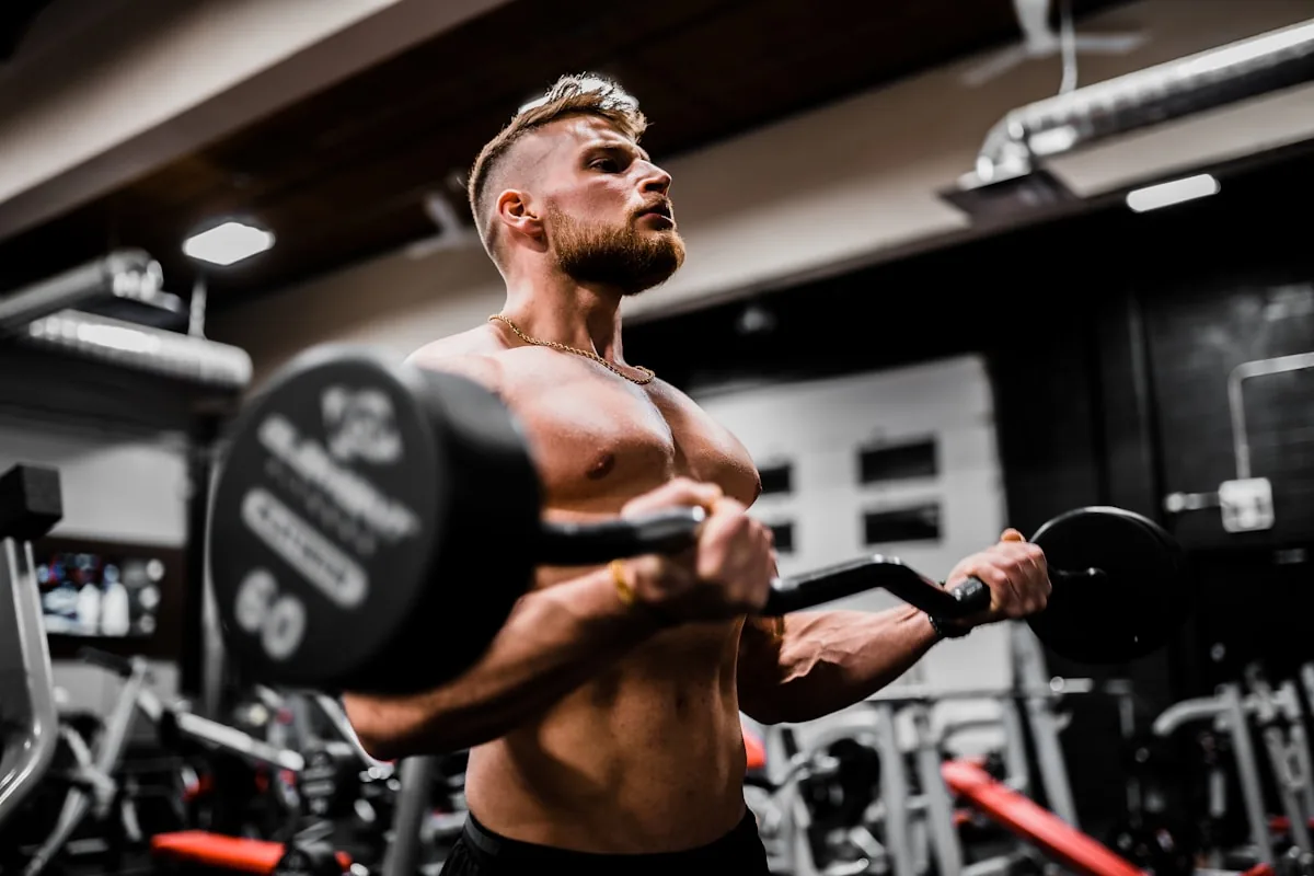 Athlete performing a barbell curl in a weight room