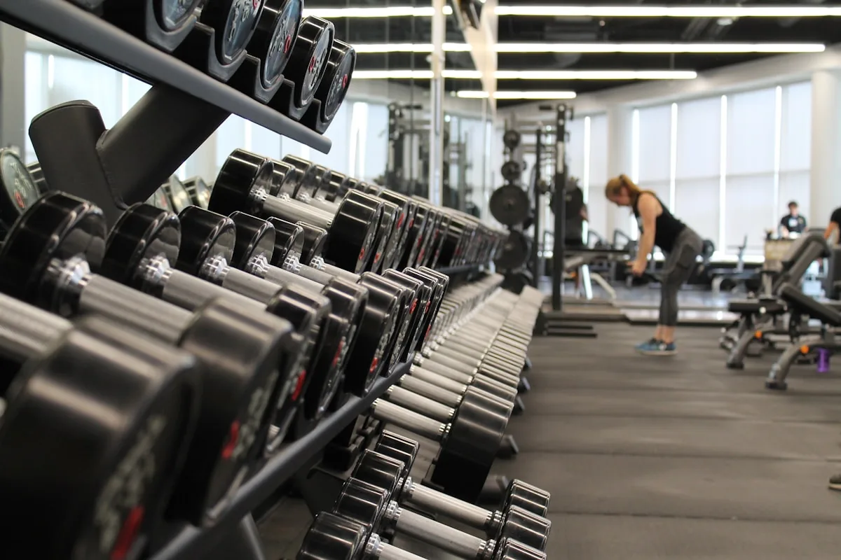 Bright strength gym with dumbbell rack and members training